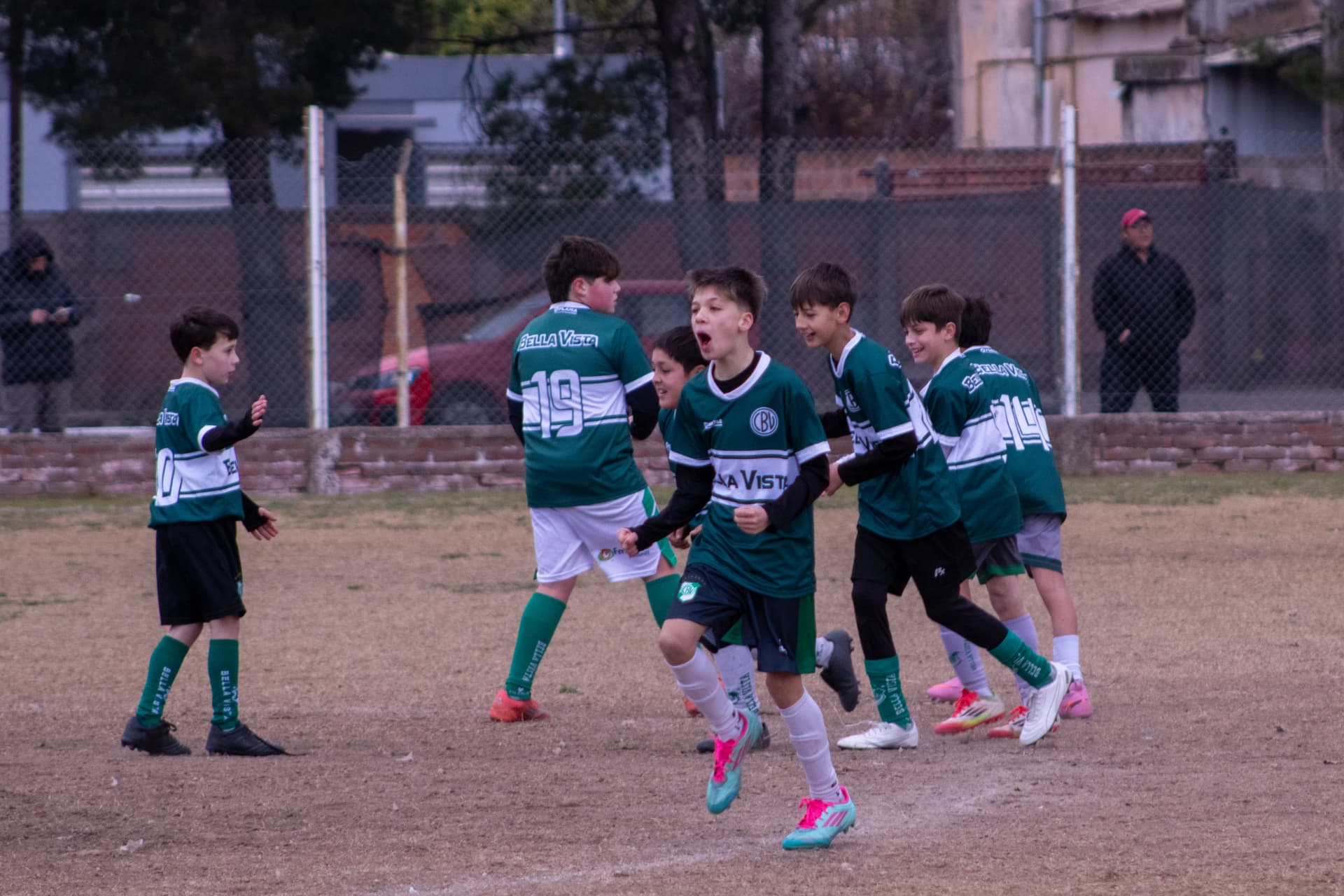 Equipo infantil de fútbol festejando un gol en la cancha