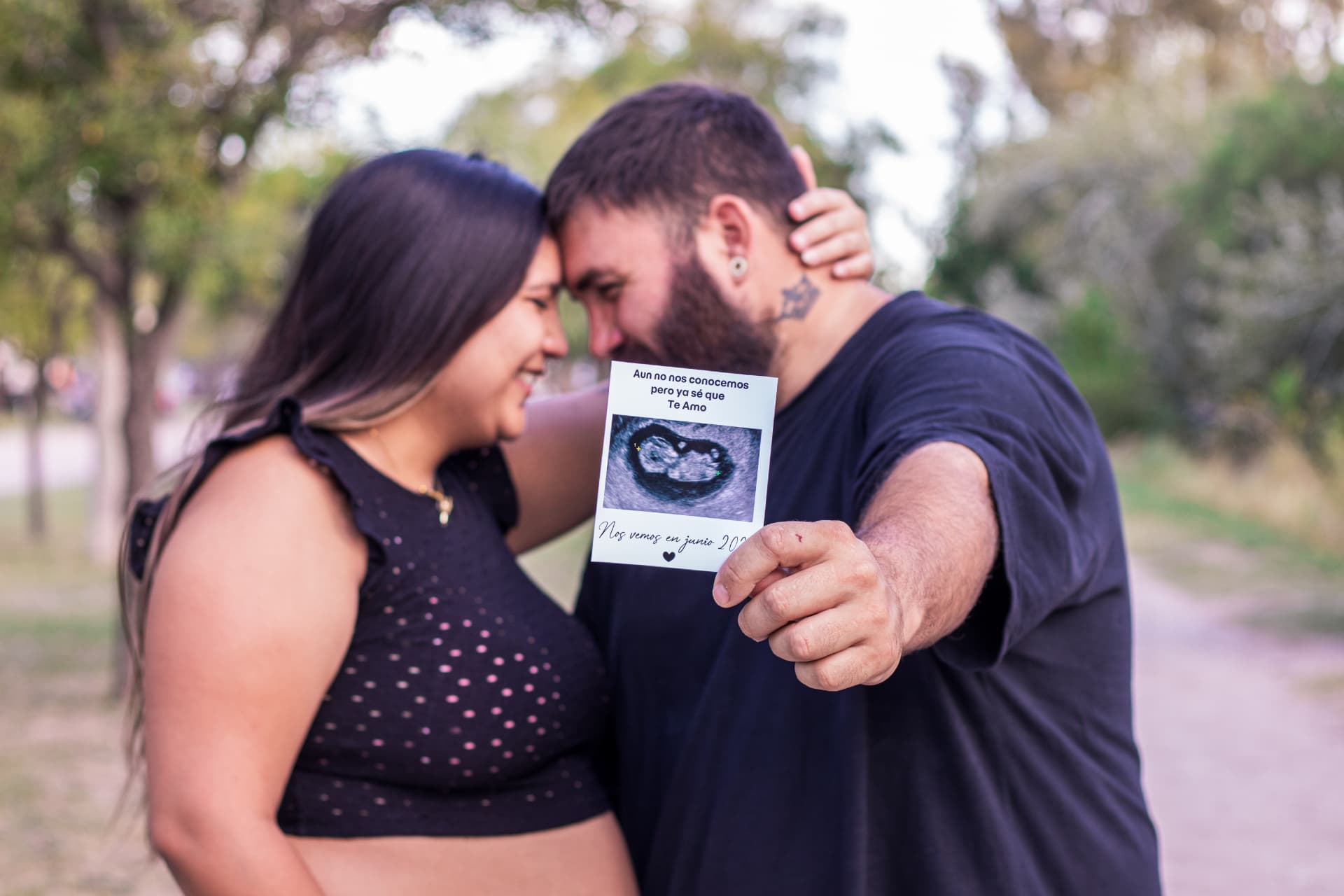 Pareja frente a frente mostrando la ecografía del bebé
