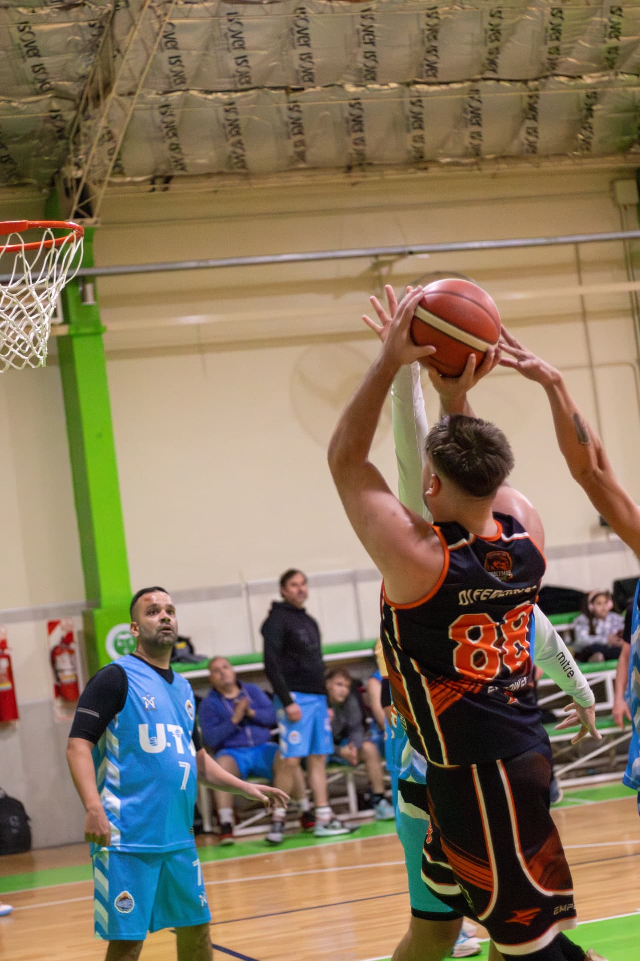 Jugador de básquet lanzando al aro con la marca de dos rivales