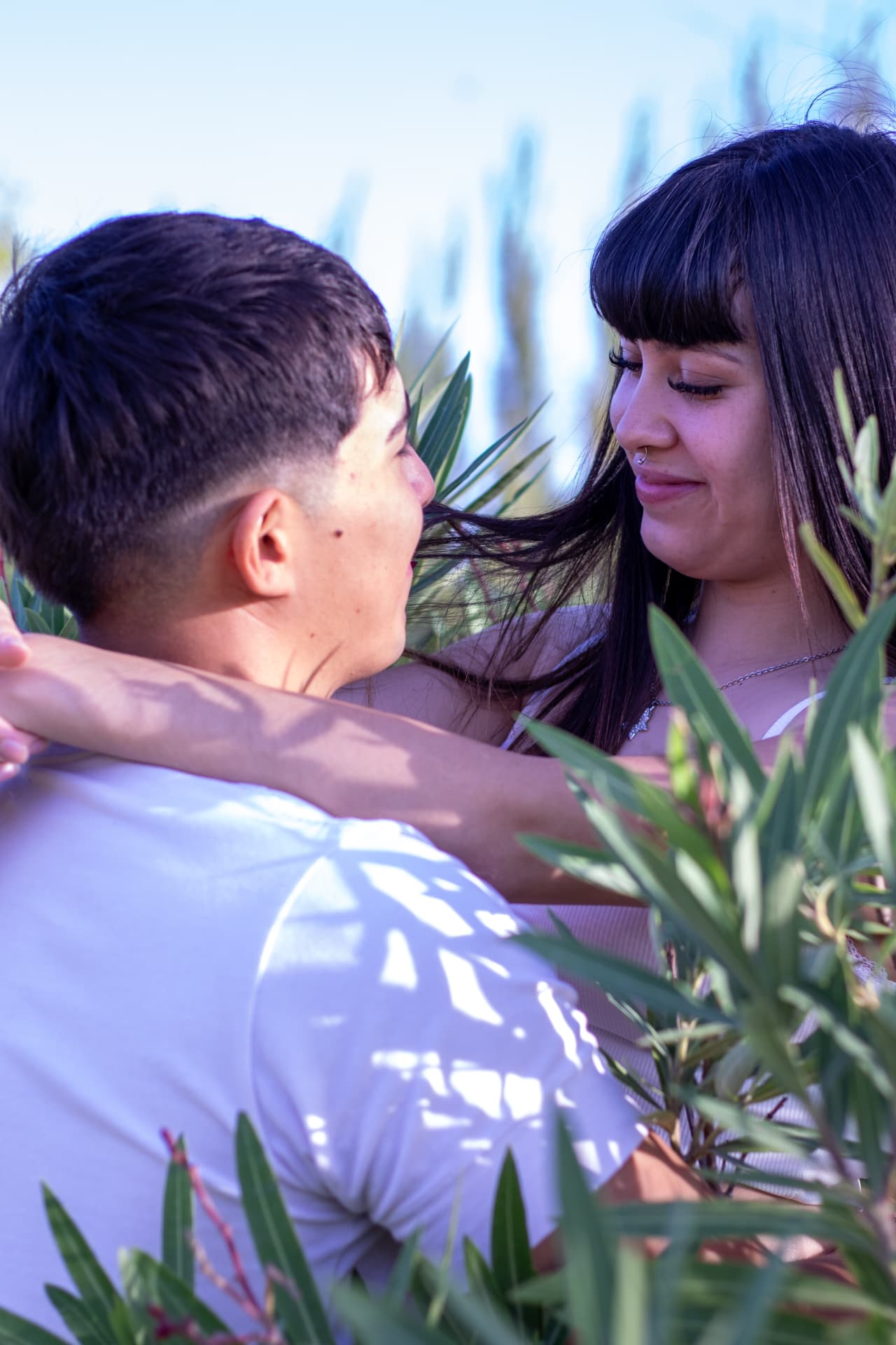 Pareja mirándose entre las hojas de una planta bajo el sol