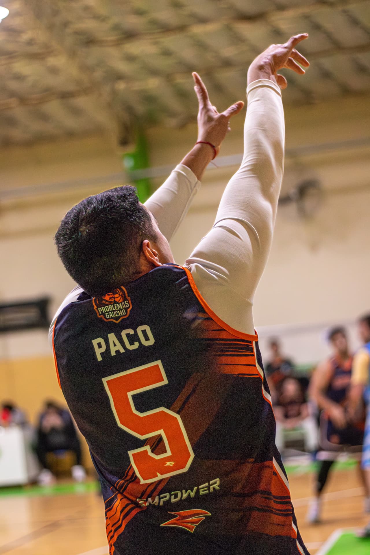 Jugador de básquet número 5 con los brazos en alto tras un lanzamiento