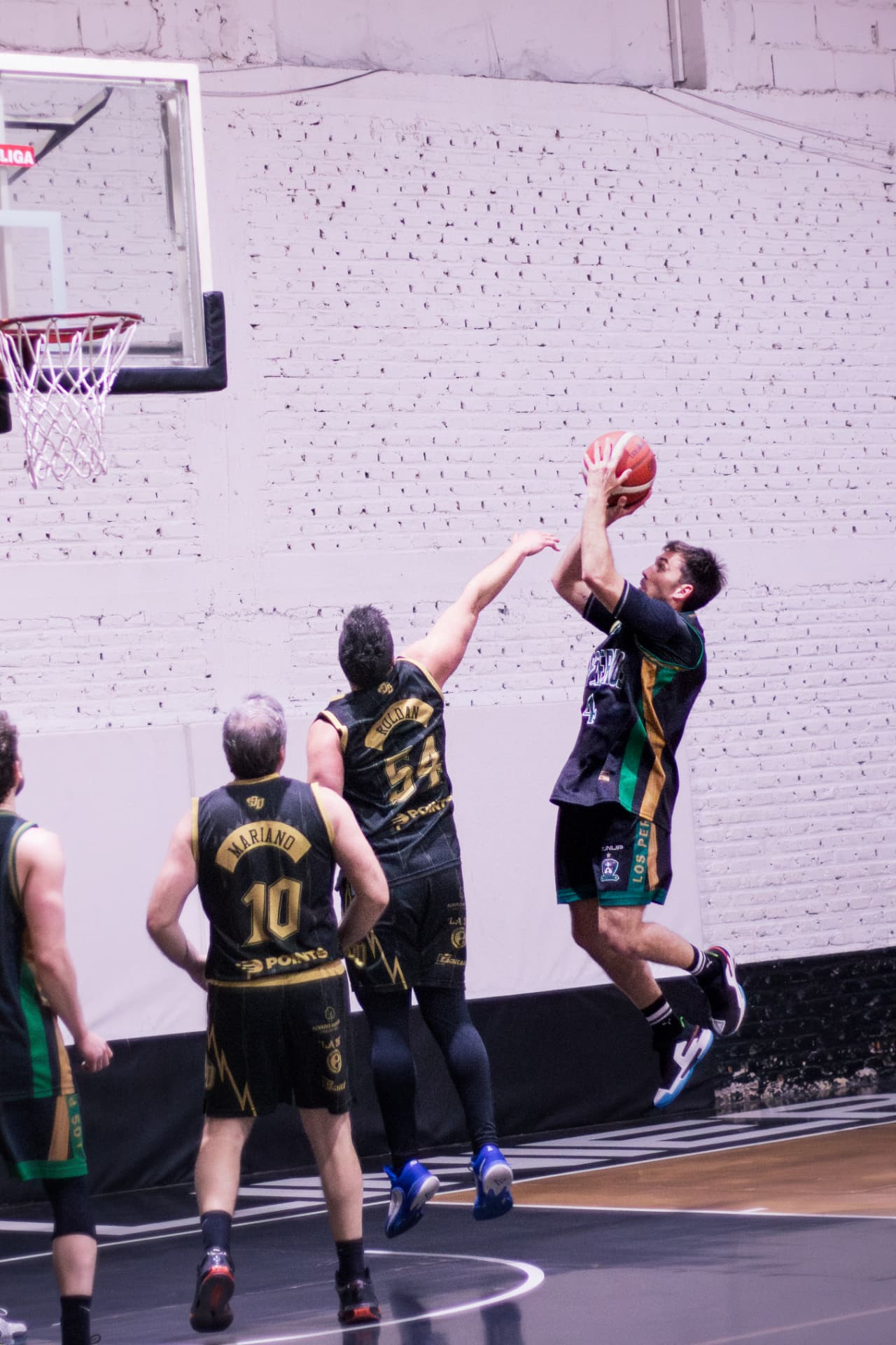 Jugador de básquet lanzando al aro ante la marca de un rival