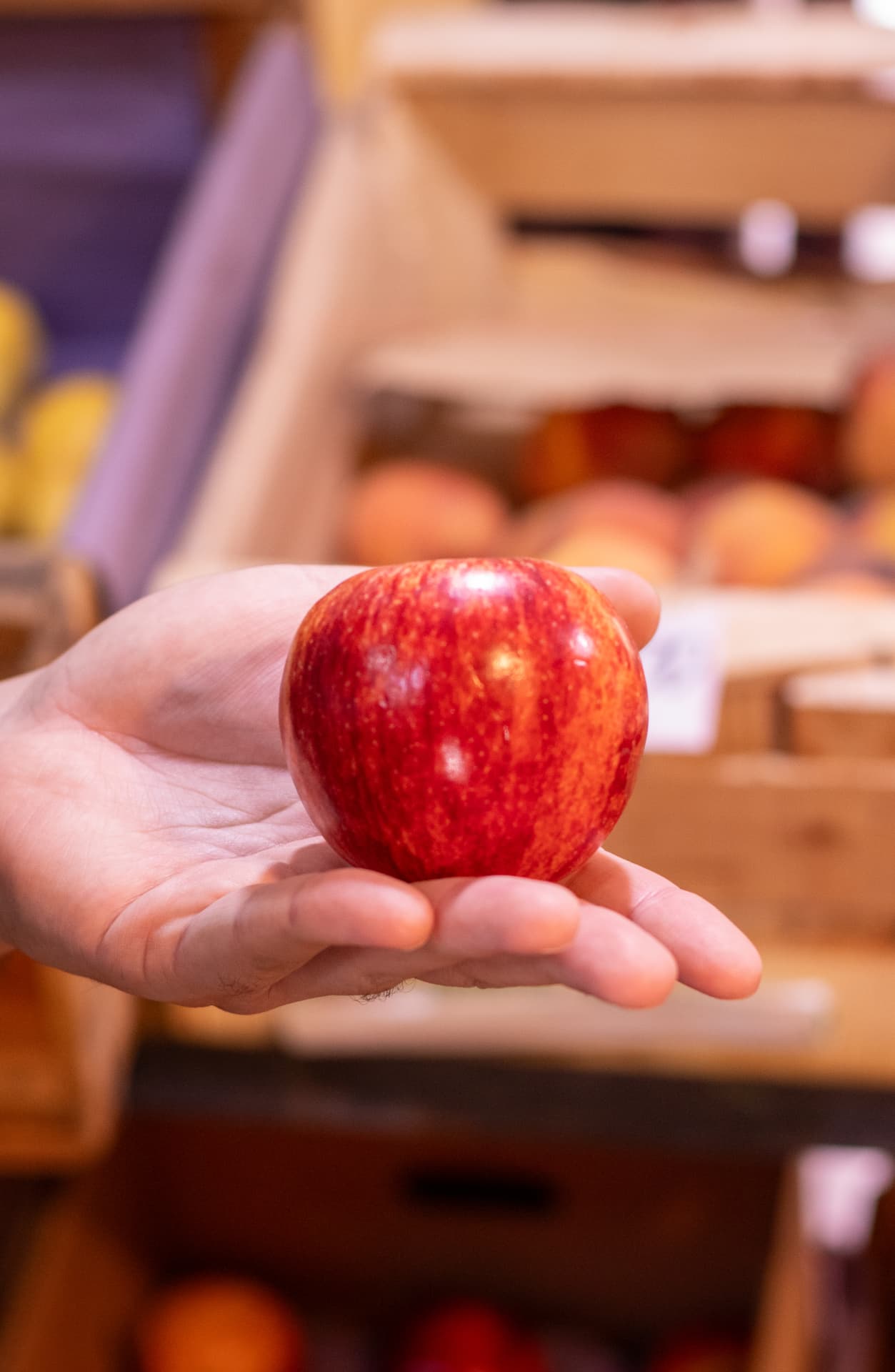 Manzana roja sostenida en la palma de la mano en la frutería