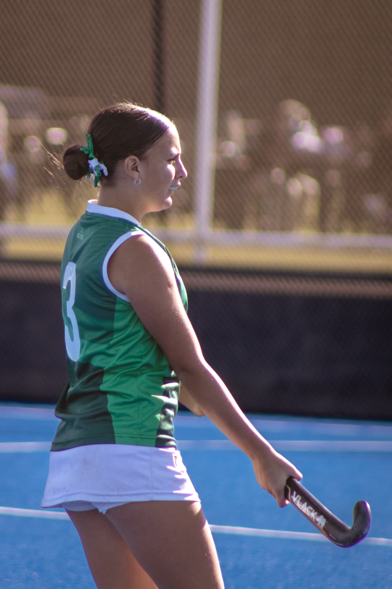 Jugadora de hockey con camiseta verde a contraluz