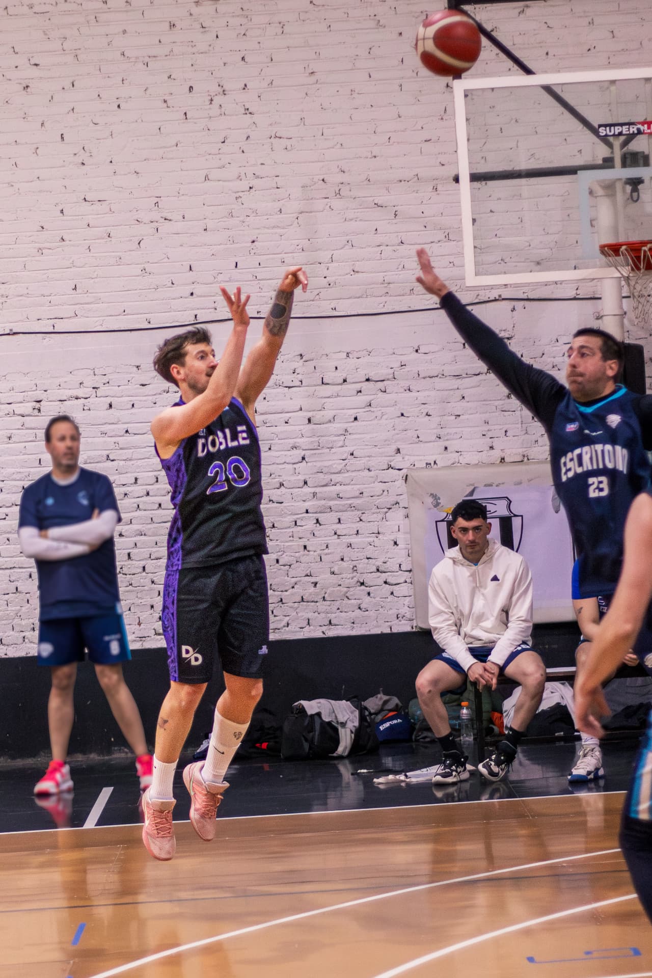 Jugador lanzando un triple con la mano del defensor en alto