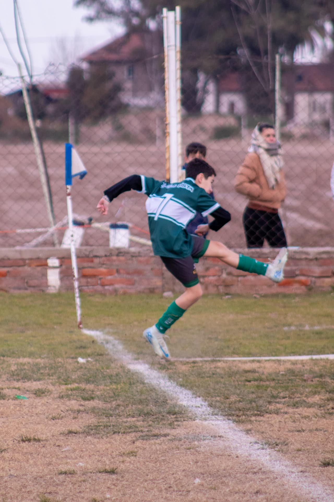 Niño futbolista rematando la pelota junto al banderín del córner