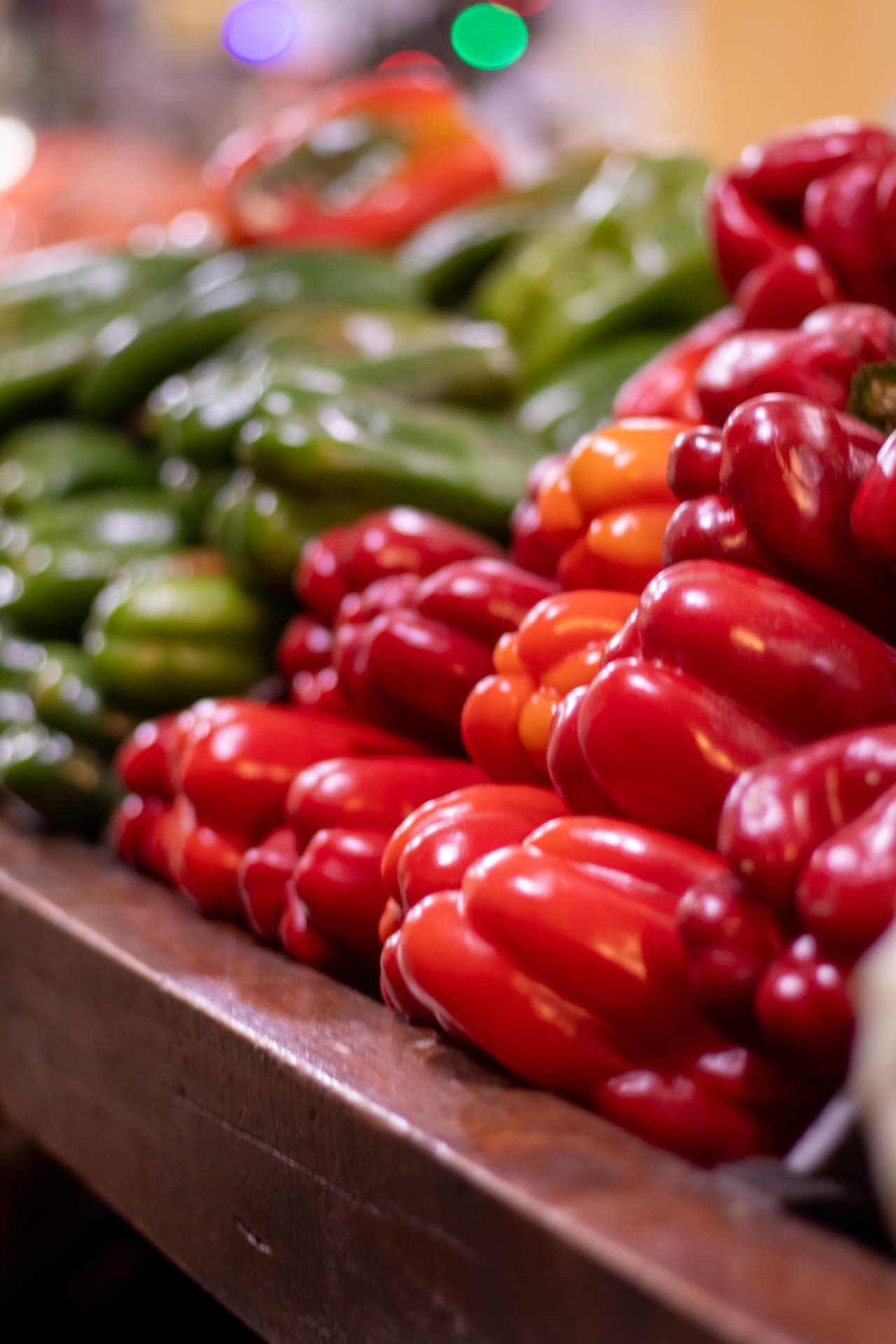Pimientos rojos y verdes apilados en el puesto de una verdulería